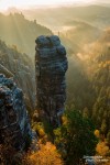 Felsnadel im Elbsandsteingebirge umgeben von golden glühendem Morgennebel und leuchtendem Herbstlaub
