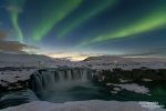 Polarlichter schießen schon in der Abenddämmerung aus dem Godafoss-Wasserfall in Nord-Island